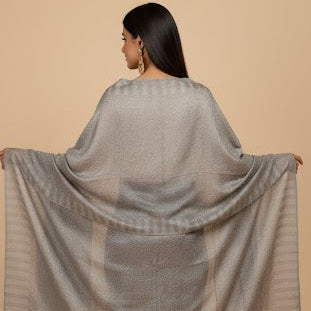 Woman wearing a light gray checkered shawl on a beige background