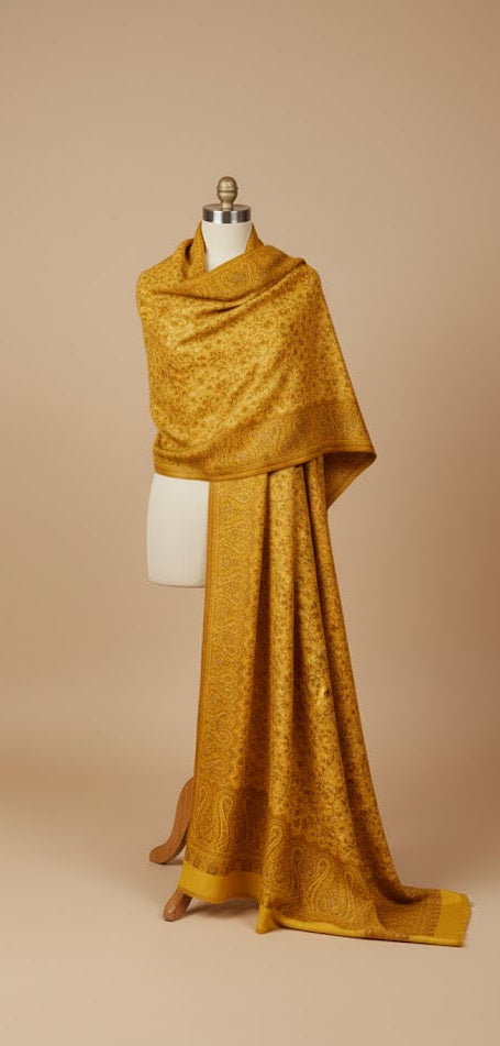 Mustard yellow shawl draped over a mannequin against a beige background