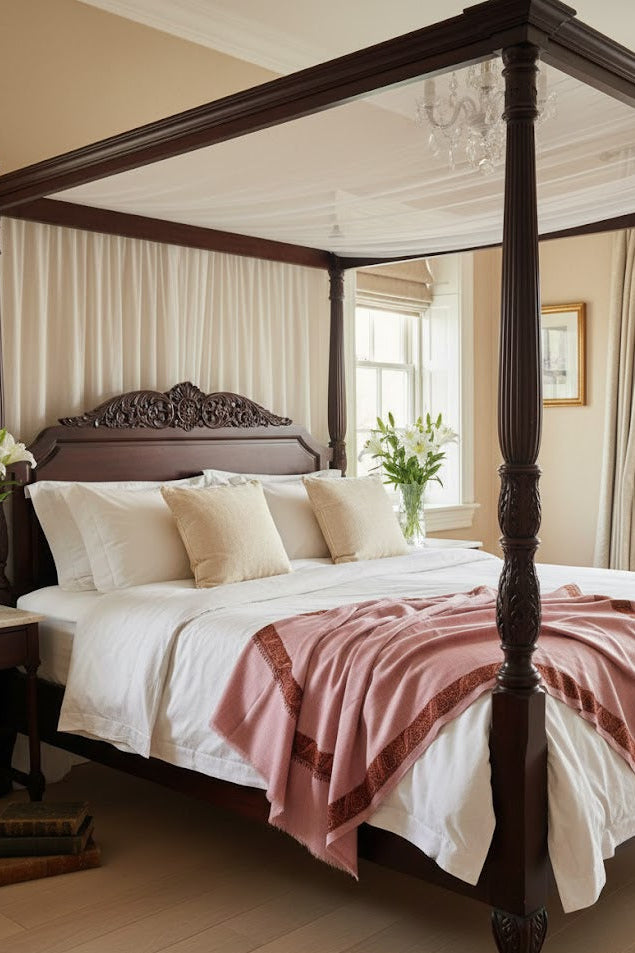 Bedroom with a four-poster bed and decorative pillows with a drape of a luxury pashmina kashmiri sozni hand embroidered border dusty pink shawl 