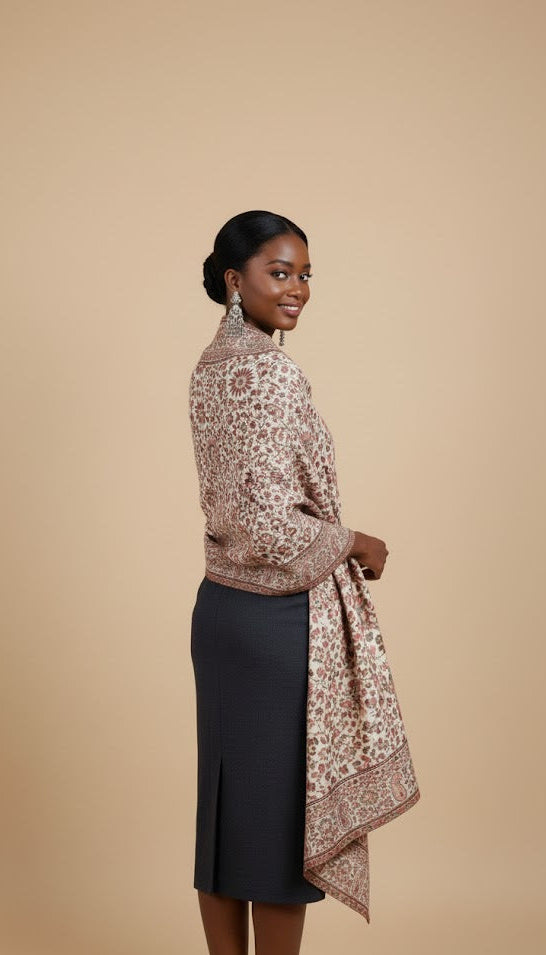 Woman wearing a patterned floral pure wool shawl in kani design over a black dress on a beige background