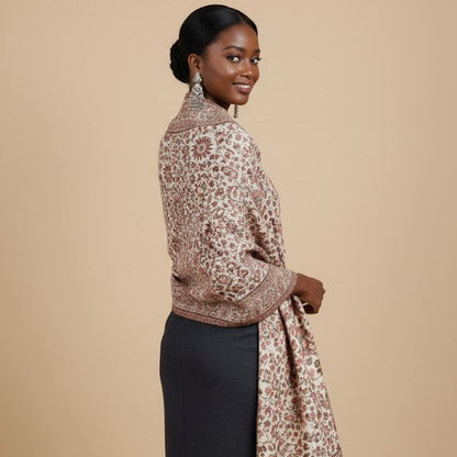 Woman wearing a patterned floral pure wool shawl in kani design over a black dress on a beige background