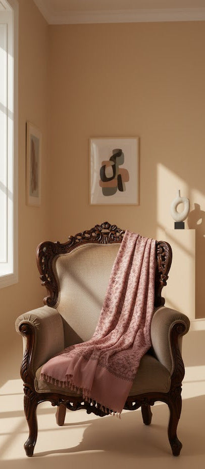 Pink shawl draped over a wooden armchair in a softly lit room.