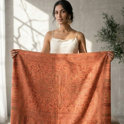 Woman holding a large orange patterned fabric in a bright room with natural light.
