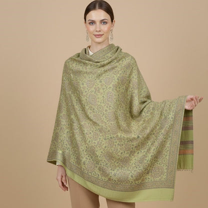 Woman wearing a sage green paisley patterned faux pashmina silk blend shawl on a beige background