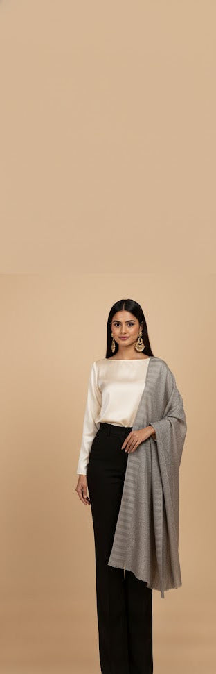 Woman wearing a white top, black pants, and a gray shawl on a beige background