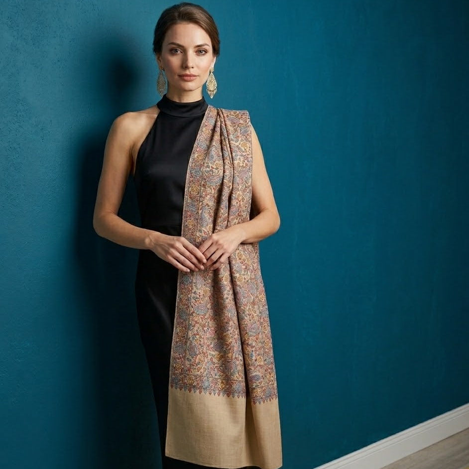 Woman wearing a patterned scarf draped over her shoulders against a blue wall.