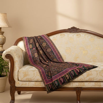 Decorative blanket with intricate patterns draped over a vintage-style sofa in a warm-toned room.