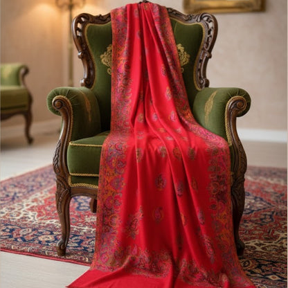 Red patterned scarf draped over a green armchair in an elegant room.