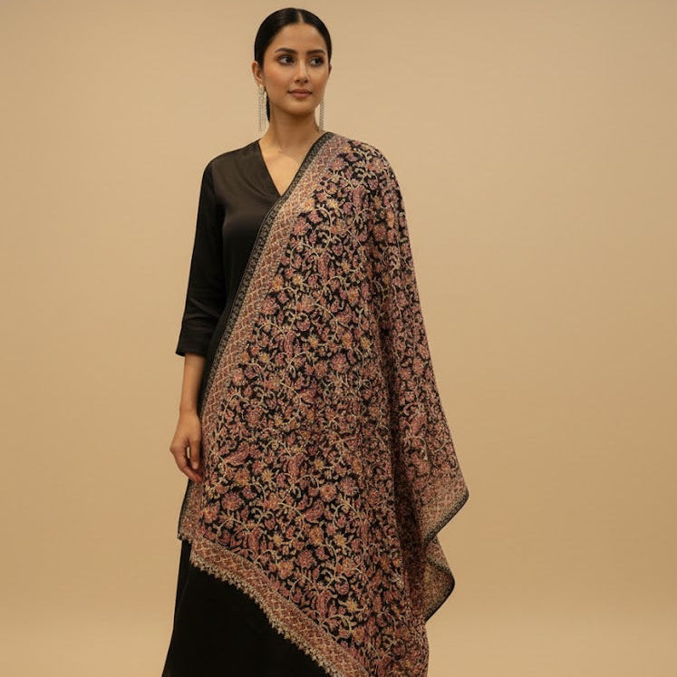Woman wearing a floral patterned shawl over a black outfit on a beige background