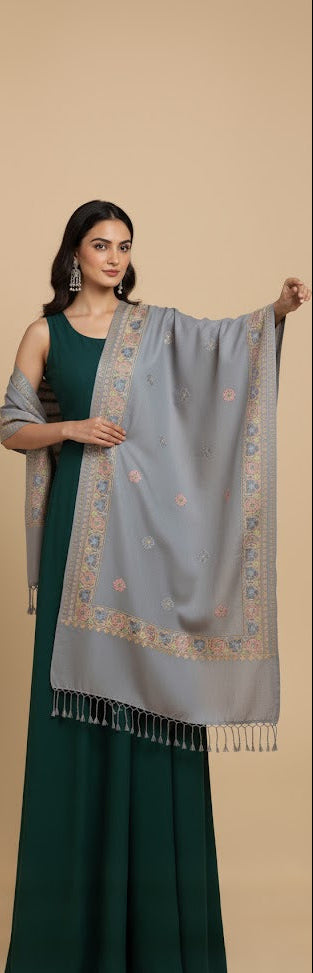 Woman holding a light blue embroidered shawl against a beige background