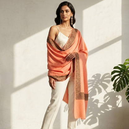 Woman wearing a peach dupatta with white outfit against a light background