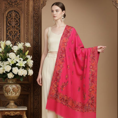 Woman wearing a cream outfit with a pink shawl in a decorated room.