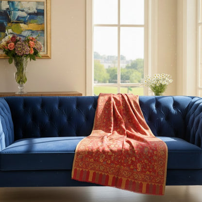 Blue sofa with a red patterned throw in a room with large windows and a painting on the wall.