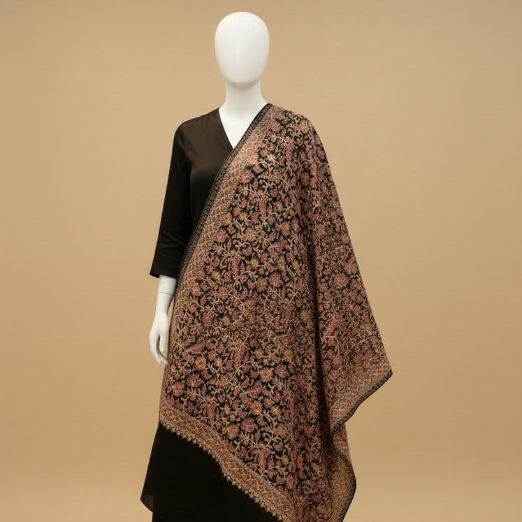 Mannequin wearing a black dress with a patterned brown shawl on a beige background