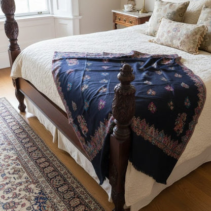Bedroom with wooden bed, patterned blanket, and nightstand with lamp.