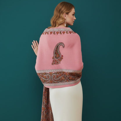 Woman wearing a pink shawl with intricate patterns on a teal background