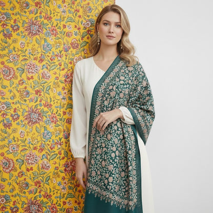 Woman wearing a green floral shawl over a white outfit against a yellow floral wall.