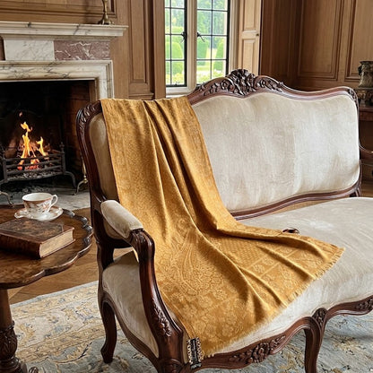 Decorative chair with a mustard yellow throw blanket in a room with a fireplace.