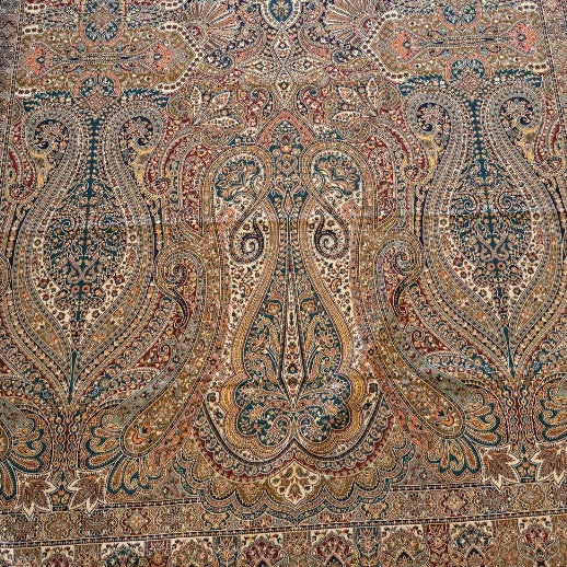 Decorative kalamkari shawl with intricate patterns on a light wooden floor.