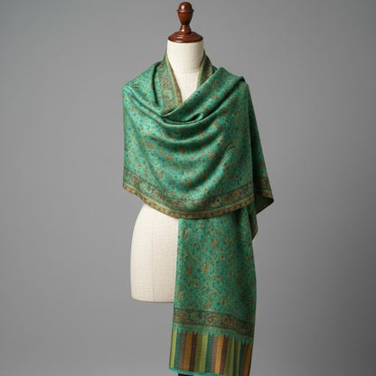Green patterned scarf on a mannequin against a gray background
