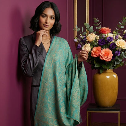 Woman holding a bouquet of flowers against a purple wall with a vase of flowers on a table.