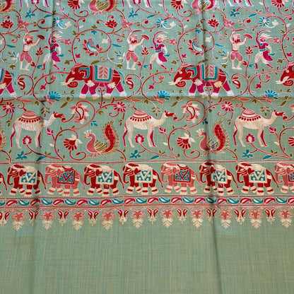 A close-up of a light sage green fabric, likely silk or satin, featuring intricate hand-woven or printed motifs in red, pink, and blue, with a decorative border on the right side.