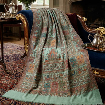 A large patterned throw blanket draped over an ornate blue velvet armchair in a classic, elegant room with a fireplace, rug, and floral arrangement.