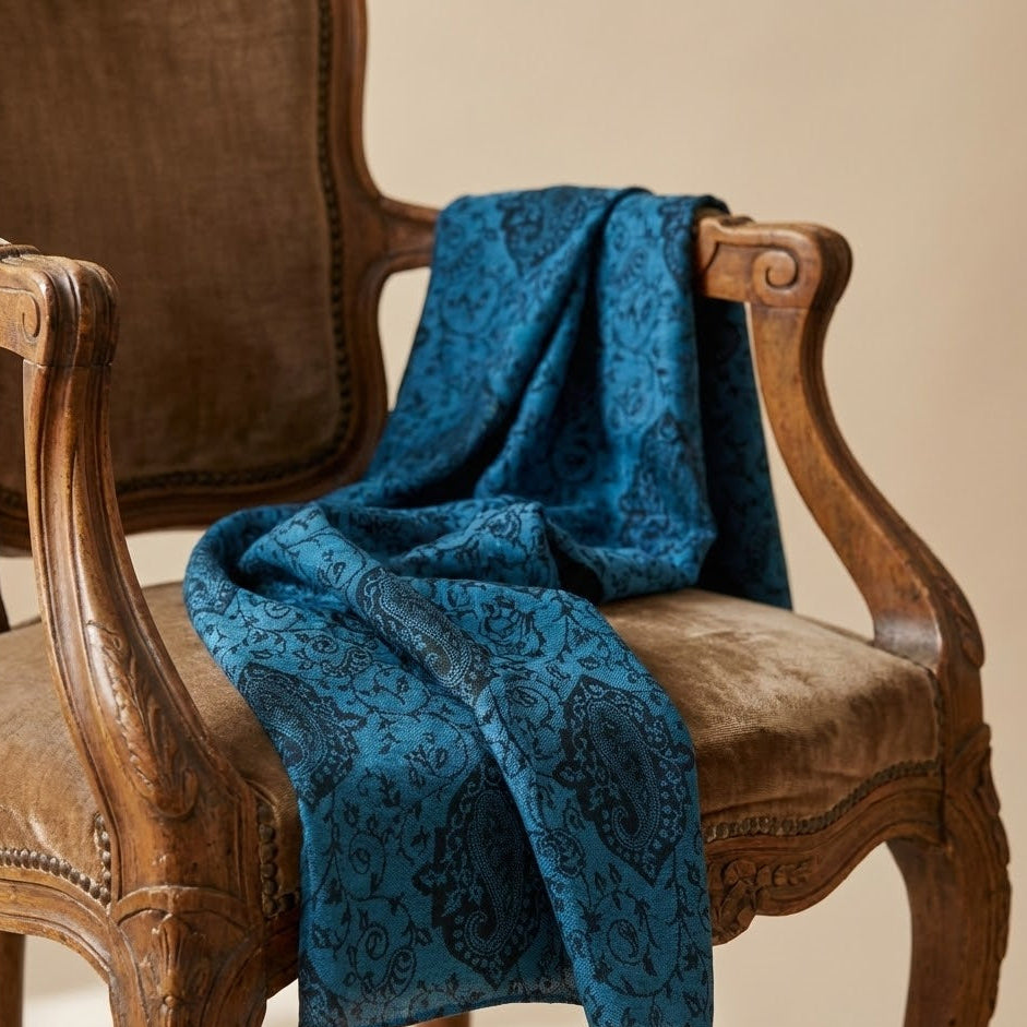 Blue patterned faux Pashmina stole draped over a wooden chair with a beige background