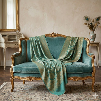 Vintage-style teal sofa with gold accents draped with a matching green fabric in a classic room.