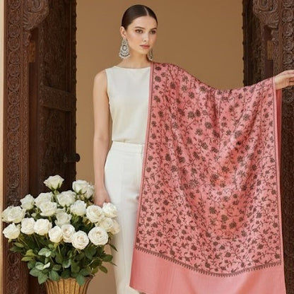 Woman holding a pink floral scarf and white roses in front of a decorative wooden door.