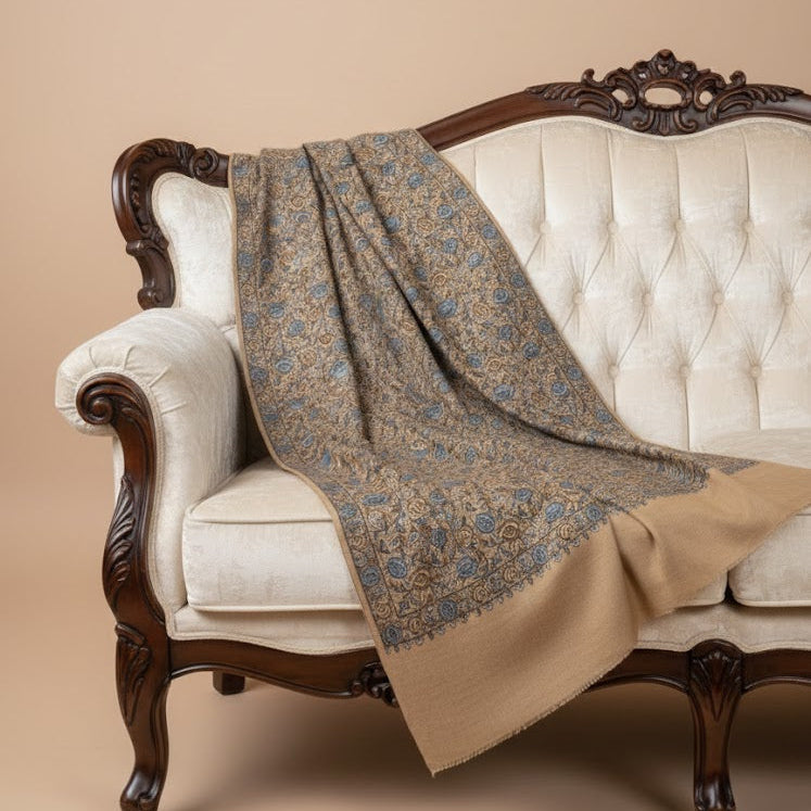 Beautiful Sozni embroidery shawl in beige with blue embroidery draped over sofa