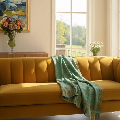 Yellow sofa with a green blanket in a bright living room with large windows.