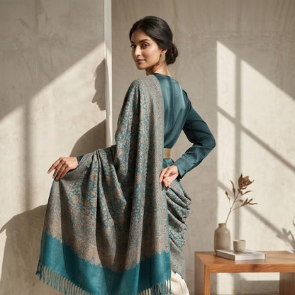 Woman holding a patterned scarf in a room with a wooden table and plant.