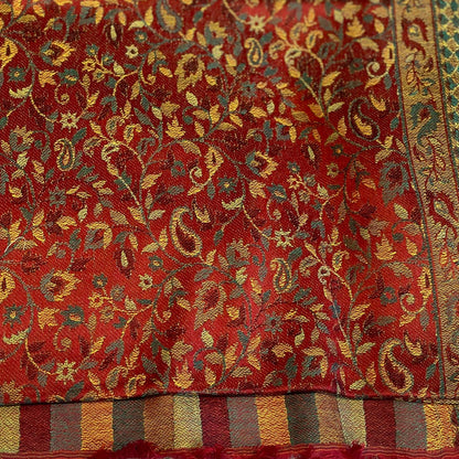 Close-up of a red fabric with intricate gold and green floral patterns