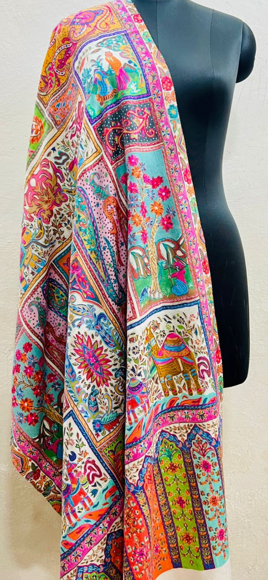 Colorful patterned shawl on a mannequin against a white background