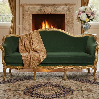 Green sofa with gold accents in a room with a fireplace and chandelier.