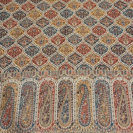 Decorative shawl with intricate patterns on a light-colored floor.