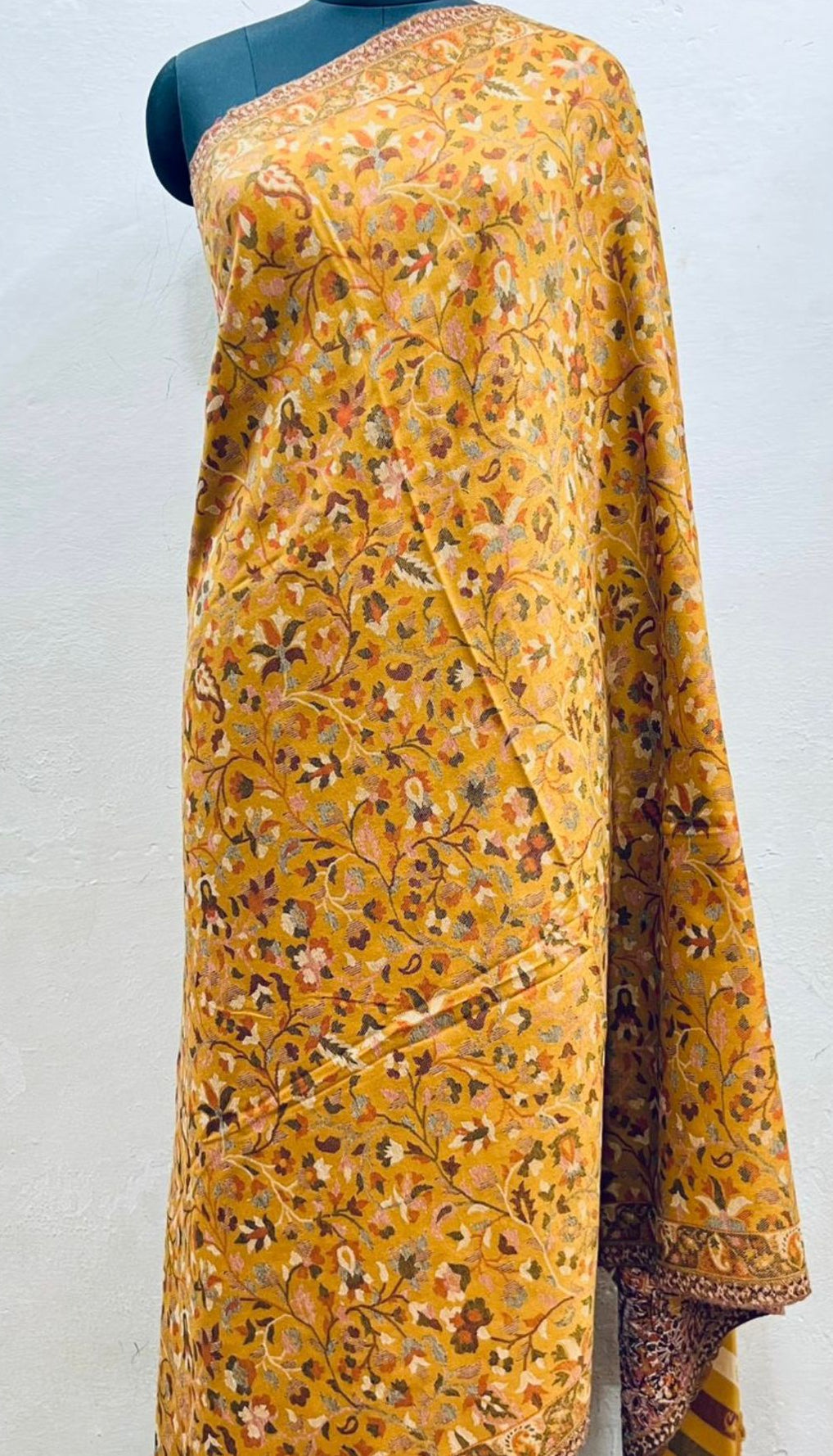 Yellow floral patterned kani design shawl on a mannequin against a white background