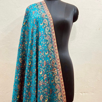 Azure blue faux Pashmina stole with intricate patterns draped over a black mannequin against a beige background