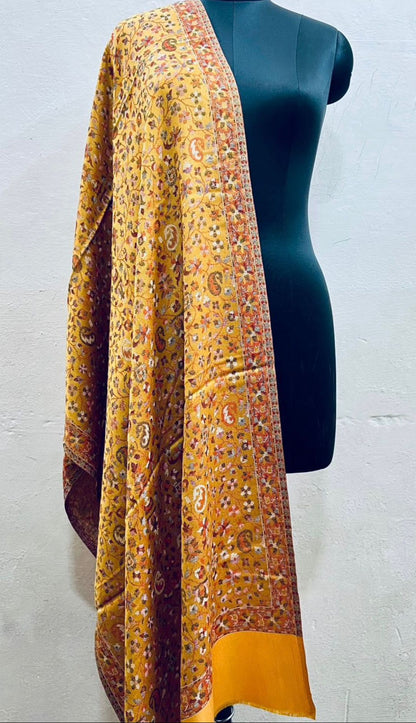 Yellow patterned stole draped over a mannequin against a white background