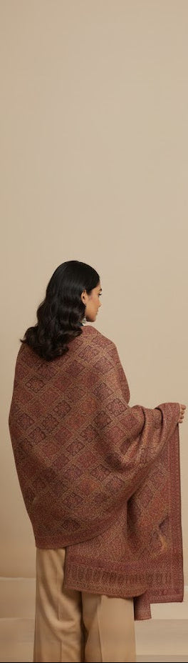 Woman draped in a pink patterned shawl against a beige background