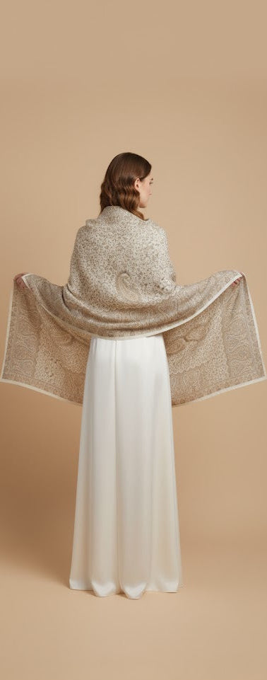 Woman wearing a beige shawl over a white dress on a beige background