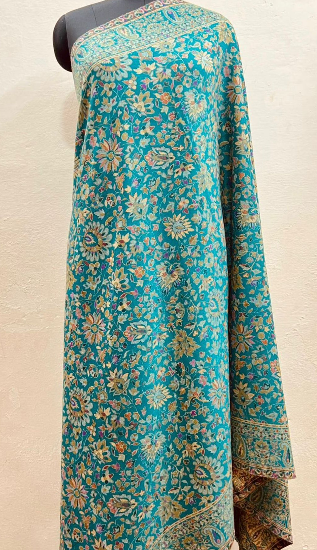 Turquoise floral patterned fabric on a mannequin against a beige background