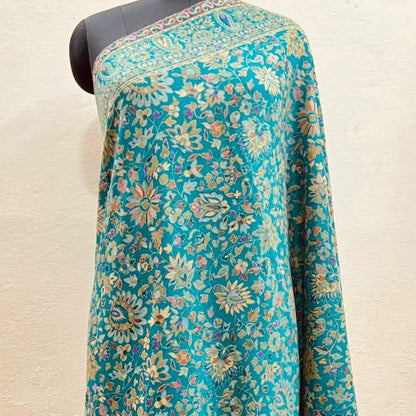 Turquoise floral patterned fabric on a mannequin against a beige background