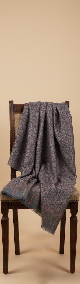 Gray patterned shawl draped over a wooden chair against a beige background