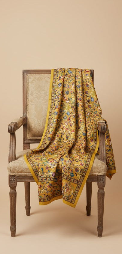 Decorative yellow patterned Shawl draped over a wooden chair against a beige background