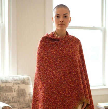 Person wearing a red patterned stole in a room with a couch and window.