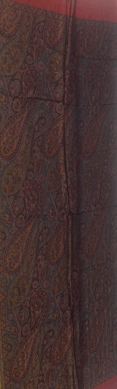 Close-up of a fabric with intricate paisley pattern in brown and red tones.