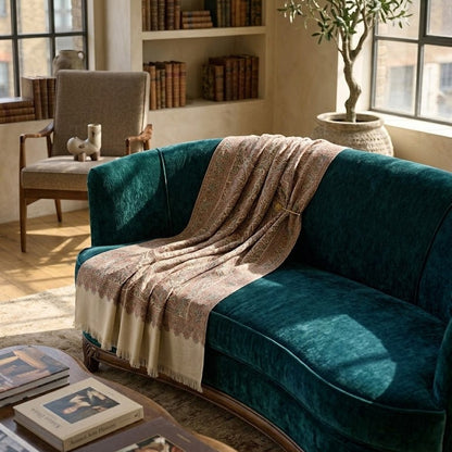 Teal velvet sofa with a beige blanket in a cozy living room setting.