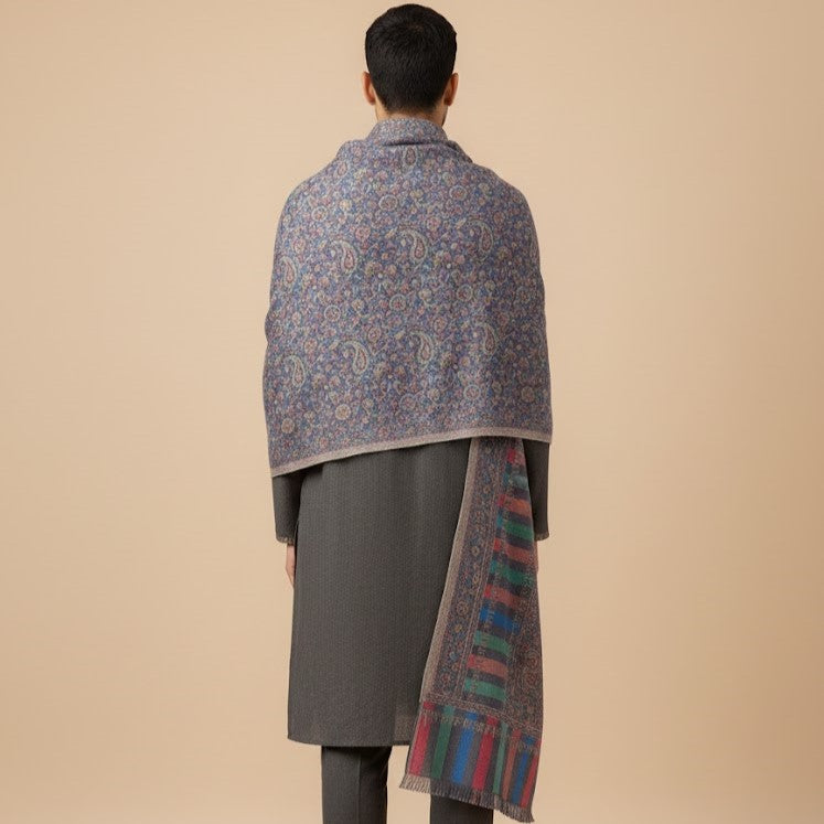 Person wearing a patterned shawl over a gray coat on a beige background